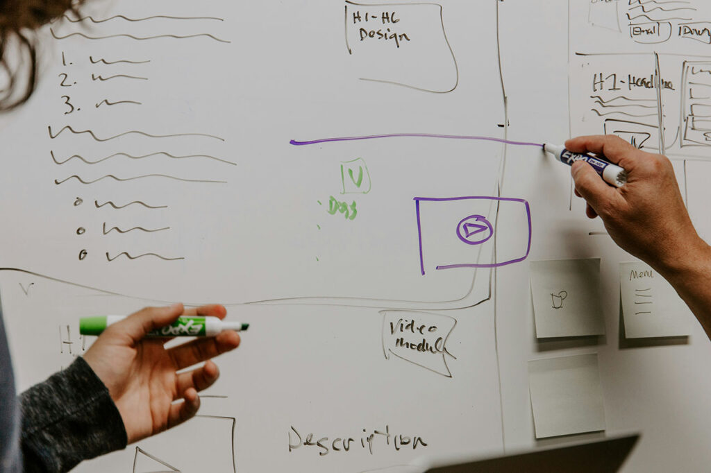 Asserting your value, an Image of two people working collaboratively at a whiteboard, both holding pens