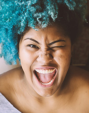 Reasons to be positive - an image of a blue-haired black woman grinning at the camera