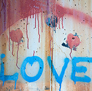 Tough Love image - a photo of the word Love spray-painted in blue on a rough, cracked and chipped plaster wall